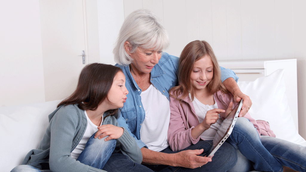 Grand-mère et petit-enfant regardant des vidéos familiales numérisées sur tablette
