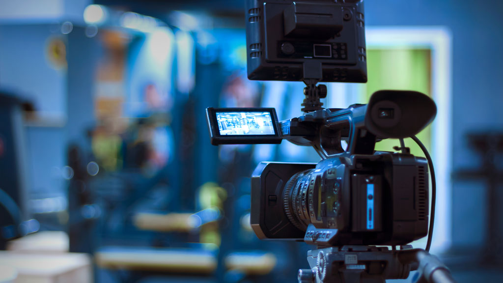 Opérateur caméra épaule filmant en extérieur avec assistant son en arrière-plan